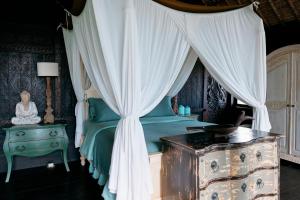 a bedroom with a canopy bed with a dresser and a table at Most Exotic Villa Keong Tabanan in Tabanan