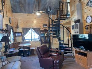 ein Wohnzimmer mit einem Ledersessel und einer Wendeltreppe in der Unterkunft Cox Cabin On The River in Red River
