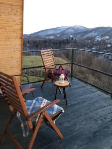 2 fauteuils à bascule et une table sur une terrasse dans l'établissement Cabana A-Frame Refugiu Montan, à Băişoara