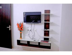 a living room with a tv on a white wall at Hotel UV, Haryana in Nārnaul