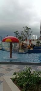 a pool with a red and yellow umbrella and water at bali residensi in Malacca