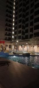 a swimming pool at night with tall buildings at bali residensi in Melaka