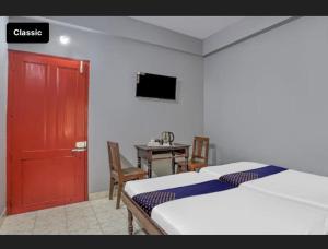 a bedroom with two beds and a table and a red door at KKP Tourist Home in Trivandrum