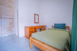 a bedroom with a bed and a dresser and a mirror at Kos Bulan Bali in Kuta