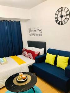 een kamer met 2 bedden en een bank en een klok bij Avida Tower Sucat, comfortable studio type in Manilla