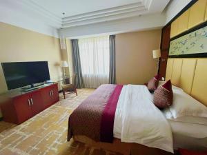 a hotel room with a bed and a flat screen tv at Jinling Jingyuan Plaza in Nanjing