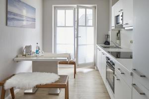 eine weiße Küche mit einem Tisch und einer Bank in einem Zimmer in der Unterkunft Techts Strandhaus in Timmendorfer Strand