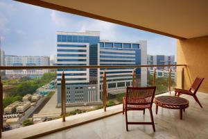 a balcony with two chairs and a view of a city at The Westin Hyderabad Mindspace in Hyderabad