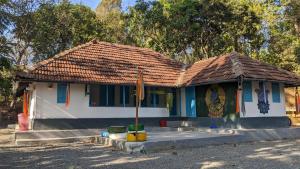 a small white house with a tile roof at Crossroads Hostel 1957 in Wayanad