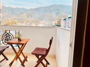 a table and chairs on a balcony with a view at Hill Nest with a serene view in Dehradun