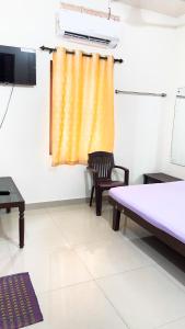 a room with a bed and a chair and a window at PPG HOMES in Ernakulam