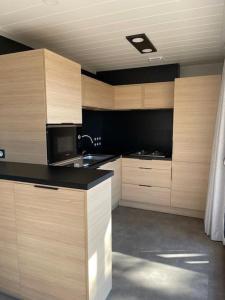eine Küche mit Holzschränken und einer schwarzen Arbeitsplatte in der Unterkunft Chalet à louer - 52m2 - Landes in Saint-Geours-de-Maremne