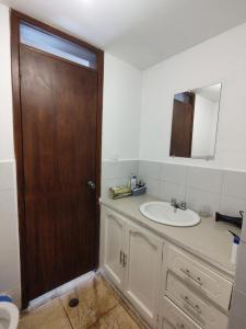 La salle de bains est pourvue d'un lavabo et d'une porte en bois. dans l'établissement Mi Casa, à Quito