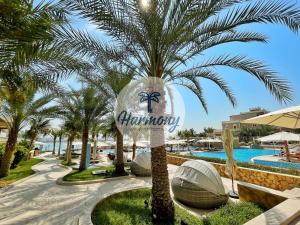 a palm tree next to a pool at a resort at Harmony Vacation Homes - BALQIS Residence in Dubai