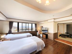 a hotel room with two beds and a flat screen tv at Hotel Tsubakino in Yamanouchi