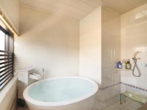 een witte badkamer met een bad en een douche bij Hotel Tsubakino in Yamanouchi