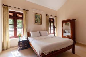 1 dormitorio con cama, espejo y ventanas en StayVista at Crystal Homestay with Breakfast & Bicycle en Madikeri