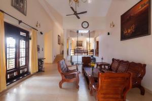 a living room with chairs and a table and a clock at StayVista at Crystal Homestay with Breakfast & Bicycle in Madikeri