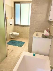 a bathroom with a bath tub and a toilet at Beach Place Apartments in Haifa