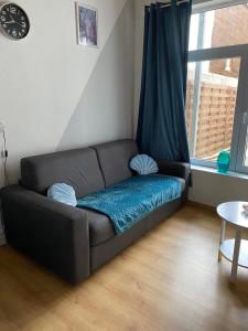 un sofá en una sala de estar con ventana en Le Rusticka en De Panne