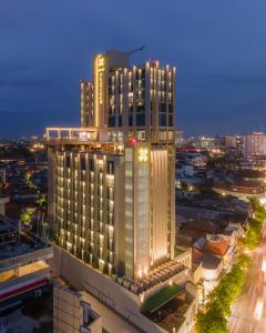 um grande edifício com um relógio sobre ele à noite em Platinum Hotel Tunjungan Surabaya em Surabaia