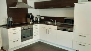 a kitchen with white cabinets and a sink at Das AMBIENTE I - Komfortables Wohnerlebnis mit Moselromantik - Herzlich Willkommen - in Zell an der Mosel