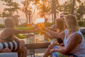 a group of people sitting around a table with drinks at 8BR West coast Phu Quoc townhouse by beach and shared swimming pools in Phú Quốc