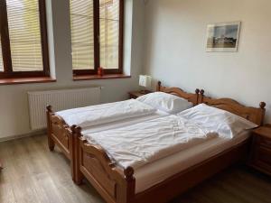 a bedroom with a bed with white sheets and two windows at Apartmán Pod Drátníkem in Svratka