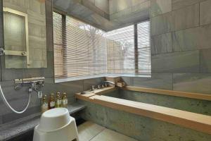 a bathroom with a bath tub and a window at 雅 南熱海 温泉別荘 Ocean View Hotspring Villa in Ajiro