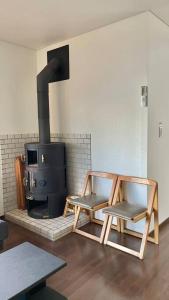 Ajiro的住宿－雅 南熱海 温泉別荘 Ocean View Hotspring Villa，客厅配有两把椅子和炉灶