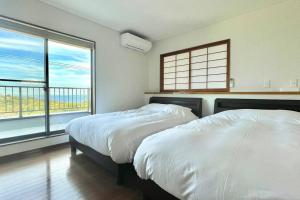 two beds in a room with two windows at 雅 南熱海 温泉別荘 Ocean View Hotspring Villa in Ajiro