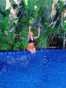 uma mulher a saltar para a água numa piscina em LaLi Home em Hanói