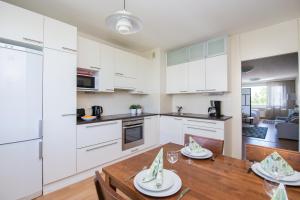 a kitchen and dining room with white cabinets and a wooden table at Kotimaailma Apartments Vaasa in Vaasa