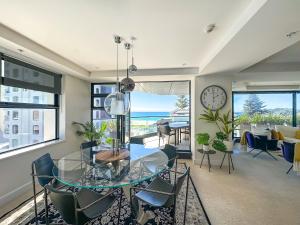 a dining room with a glass table and chairs and a clock at Mt Maunganui Main Beach Luxury with Seaviews in Tauranga