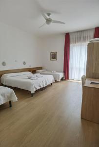 duży pokój z 2 łóżkami i oknem w obiekcie Albergo Miralaghi w mieście Padergnone