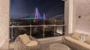 a balcony with two chairs and a view of a city at Yeongdo Grandbern Hotel in Busan