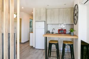 a kitchen with wooden cabinets and a counter with stools at Apartamento a un paso del mar in Málaga