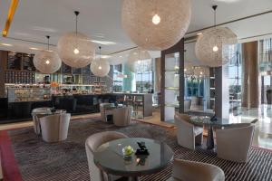 un restaurante con mesas, sillas y lámparas de araña en Park Rotana Abu Dhabi en Abu Dabi