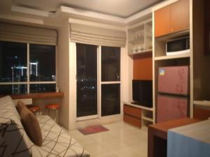 a room with a bed and a kitchen with windows at Tifolia Apartment Pulomas - Kelapa Gading in Jakarta