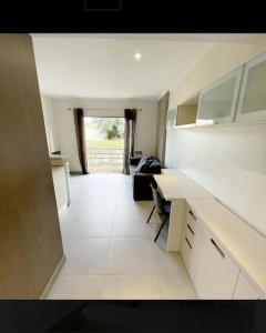 uma cozinha com balcões brancos e um quarto com uma janela em Studio climatisée dans résidence à 5 minutes des plages a pied em Propriano