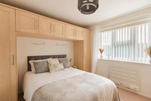 Un dormitorio con una gran cama blanca y una ventana en Surrey Stays - 2Bed house, 2 parking spaces, RH1, near Gatwick Airport, en Redhill