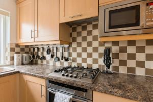 a kitchen with a stove and a microwave at Surrey Stays - 2Bed house, 2 parking spaces, RH1, near Gatwick Airport in Redhill