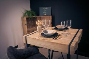 a wooden table with wine glasses and plates on it at Maison avec jacuzzi privatif in Renac