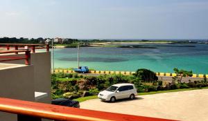 a white car parked in a parking lot next to the water at The House Pension in Jeju