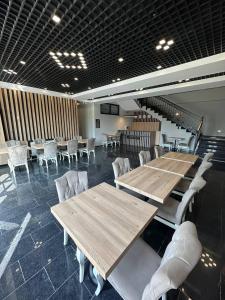 une salle à manger avec des tables en bois et des chaises blanches dans l'établissement Akel Guest House, à Tekirdağ