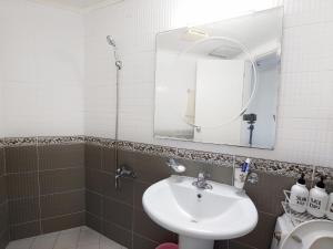 a bathroom with a sink and a mirror and a toilet at The House Pension in Jeju