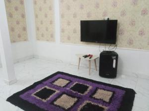 RD Cottage Valley في بوغور: غرفة بها سجادة أرجوانية وجهاز تلفزيون +4 صور