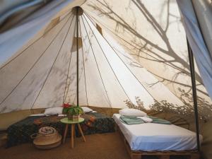 Nisi Glamping في باراليا راشون: خيمة فيها سريرين وطاولة فيها
