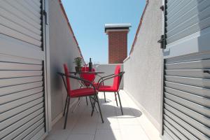 un patio con sillas rojas y una mesa en el balcón en Luxury Apartments Elizabeth, en Podstrana