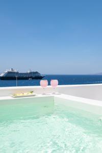 dwa kieliszki wina siedzące na krawędzi basenu w obiekcie Porto Mykonos w mieście Mykonos